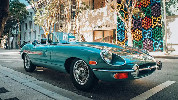 A turquoise classic Jaguar parked on a street